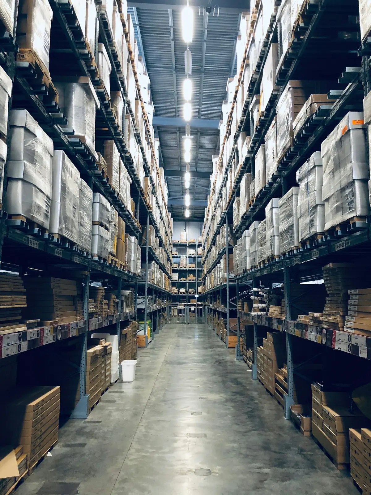 A distribution center aisle lined with pallet racking stacked with cases of grocery products