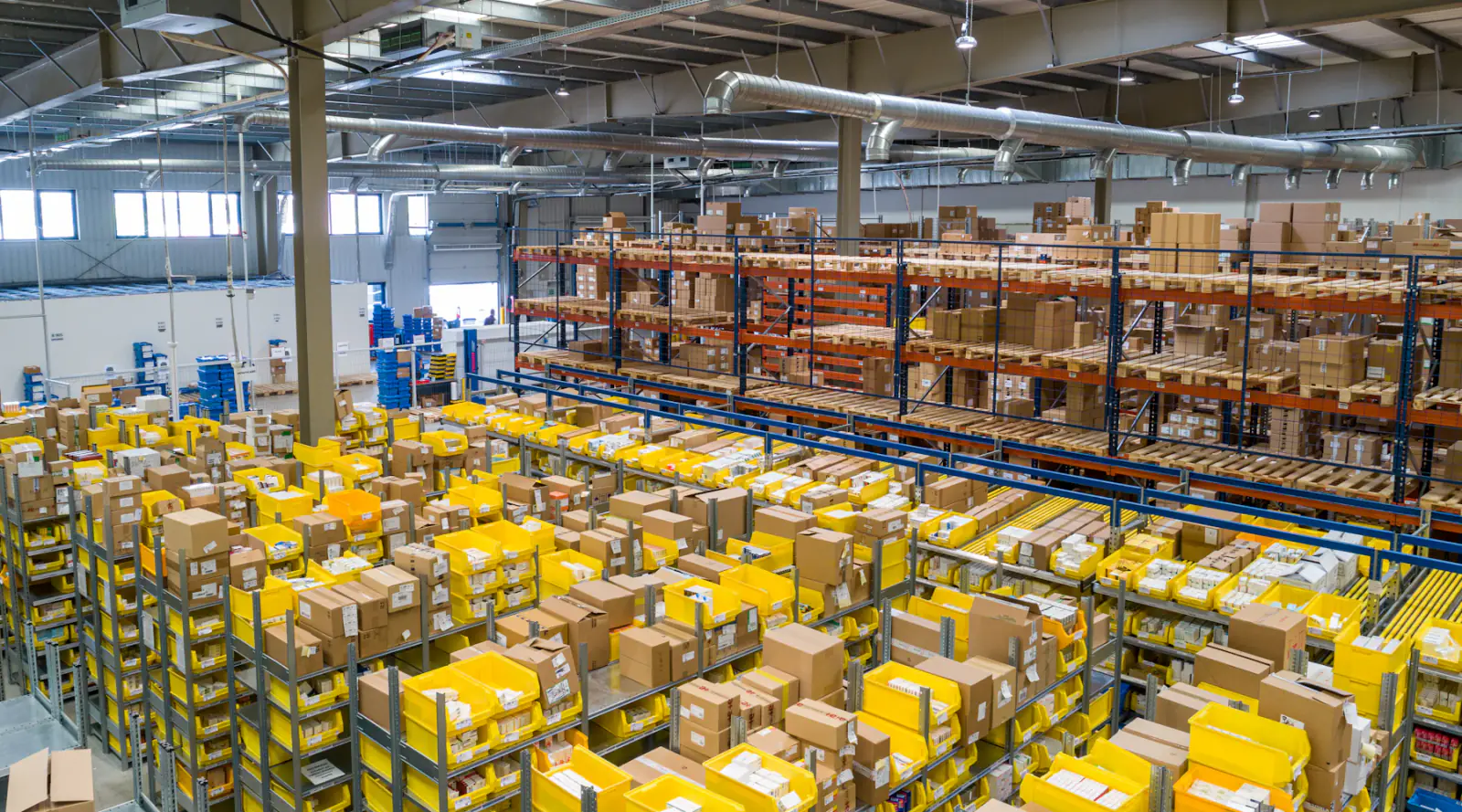 Cases and totes staged for grocery order picking in a distribution warehouse